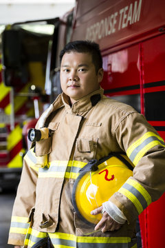 Serious Chinese fireman standing near fire truck