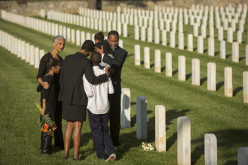 Multi-generation Black family hugging in military cemetery