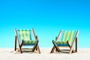 Two sunbeds at the beach on background of blue sky