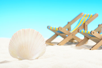 Seashell and two sunbeds at the beach on background of blue sky