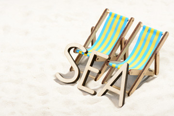 The word SEA and two sunbeds at the beach