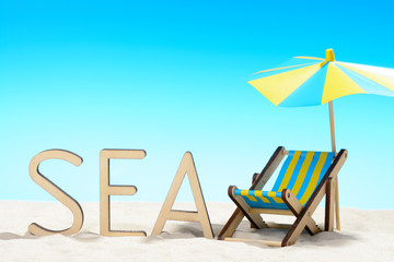 The word SEA and sunbed at the beach on background of blue sky