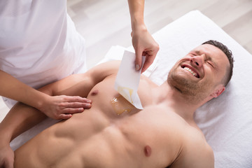 Person Waxing Man's Chest With Wax Strip