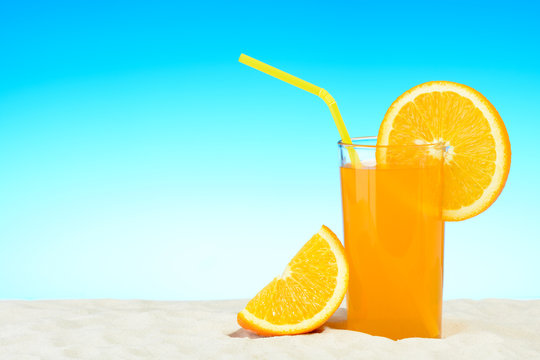 A glass of orange juice on the beach