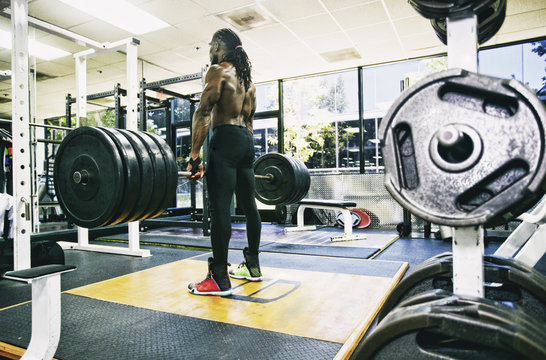 Black man lifting barbell in gymnasium - Powered by Adobe