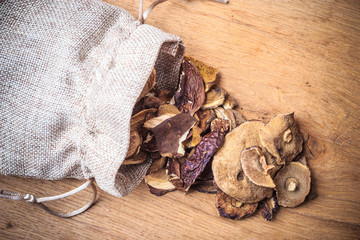 Dry mushrooms in sack on wooden table.