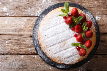 Victoria sandwich cake, decorated with strawberries, cranberries and mint closeup. Horizontal top view