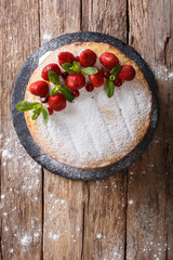 Home Victoria sponge cake, decorated with strawberries and mint closeup. Vertical top view