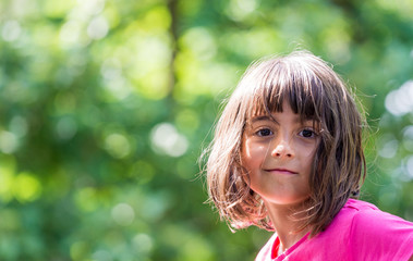 Beautiful little girl smiling in the park looking to camera