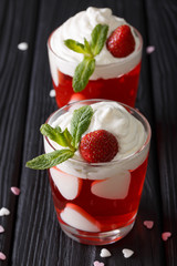 Strawberry jelly with whipped cream, decorated with hearts and fresh mint close up. vertical