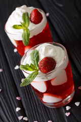 beautiful strawberry cocktail with whipped cream and mint, decorated with hearts close-up. vertical