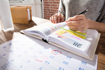 Businesswoman Marking Schedule On Calendar