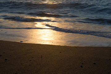 Sunset light on gentle waves on a sandy shore