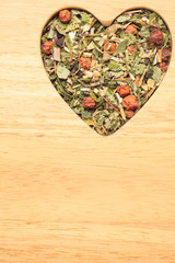 Dried herb leaves heart shaped on wooden surface