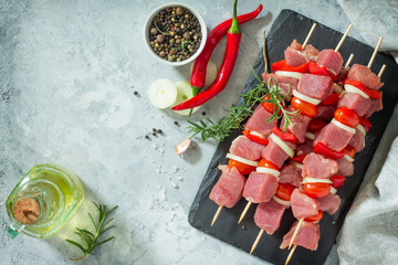 Fresh meat kebab. Meat fillet raw with cherry tomatoes, onions, spices and rosemary on a cutting board, preparation of barbecue. Copy space. Top view.