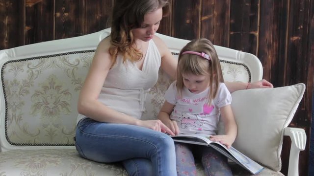 A young mother reads a book with a little daughter