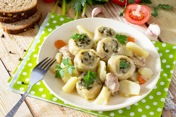 Potatoes stewed with meat and rolls of dough with garlic and greens on a wooden table, served with fresh vegetables. Nudley is a national Ukrainian dish.