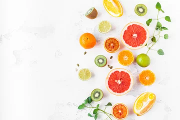 Photo sur Plexiglas Fruits Fruit background. Colorful fresh fruit on white table. Orange, tangerine, lime, kiwi, grapefruit. Flat lay, top view, copy space
