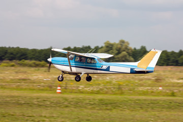 Fototapeta na wymiar Small private airplane landing on the grass field