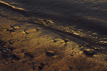 Soft wave of sunset ocean on sandy beach.