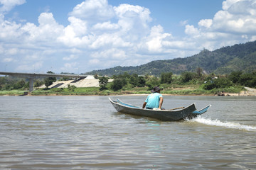 Fototapeta premium Man on wooden fishing boat on the river in North of Thailand, outdoor day light