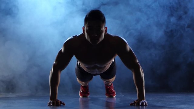 Asian bodybuilder man push ups. Black smoke background. Silhouette