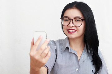 Beautiful woman wearing eyeglasses using a smart phone sitting on a sofa