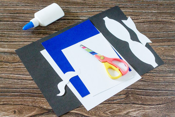 The child cuts out paper parts. Greeting card for Father's Day. Made by own hands. Children's art project, a craft for children. Craft for children.