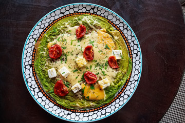 Spinach omelette with tomatoes and cheese on top