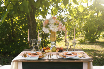 A festively furnished table for two persons standing in a summer green garden on a sunny day