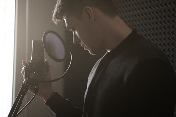 The guy is holding a microphone standing on the counter, bending his head in the rays of the sun