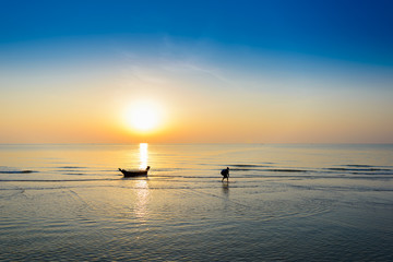 Silhouette of fishing boat and Beautiful tropical sunrise on the beach.