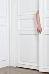 Fototapeta na wymiar A female hand between two shutters closed white doors.