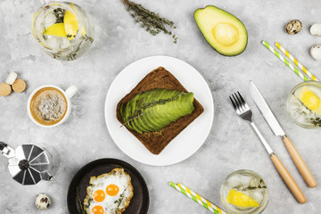 Traditional breakfast - toast from rye bread with avocado, fried eggs from quail eggs,  lemonade on a light background. Top view. Food background