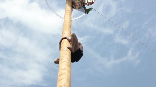 Barefoot Man Gets down from High Smooth Pole with Decoration