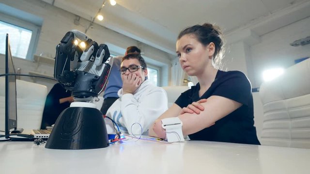 The robot hand is moving following the movements of the disabled girl's arm in laboratory.