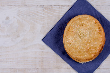 Round puff pastry with sesame on the napkin over wooden background