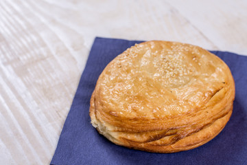 Round puff pastry with sesame on the napkin over wooden background