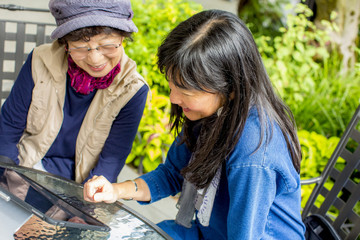 Older Japanese mother and daughter using digital tablet