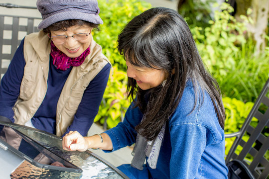 Older Japanese mother and daughter using digital tablet