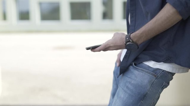 Junger Mann holt Smartphone aus der Hosentasche raus