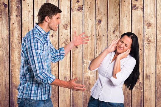 Angry man arguing with woman against wooden wall