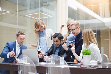 happy business team enjoy good news together in modern office with laptop