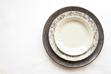 Stack of empty ceramic plates isolated on white background with copy space. Stylish gray dishes decorated with floral pattern. Beautiful vintage crockery top view