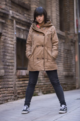 Young modern looking woman staring at camera, with a coat.