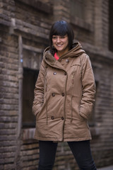 Young modern looking woman staring at camera, with a coat.