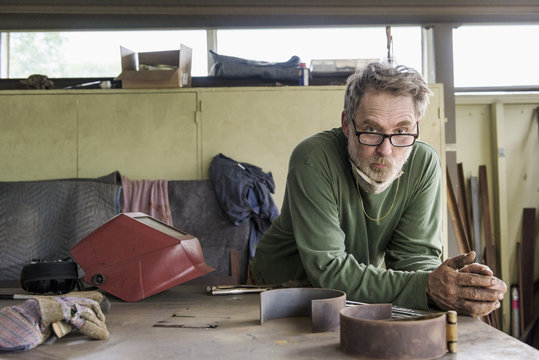 Man leaning on table in workshop