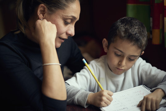 Mother watching son practicing writing alphabet