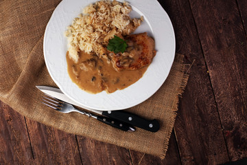 Delicious rice with chicken and vegetables on plate on wooden table
