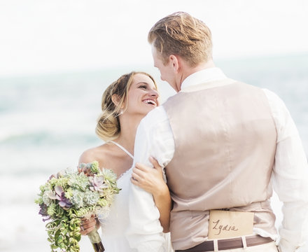 Caucasian bride and groom hugging on beach